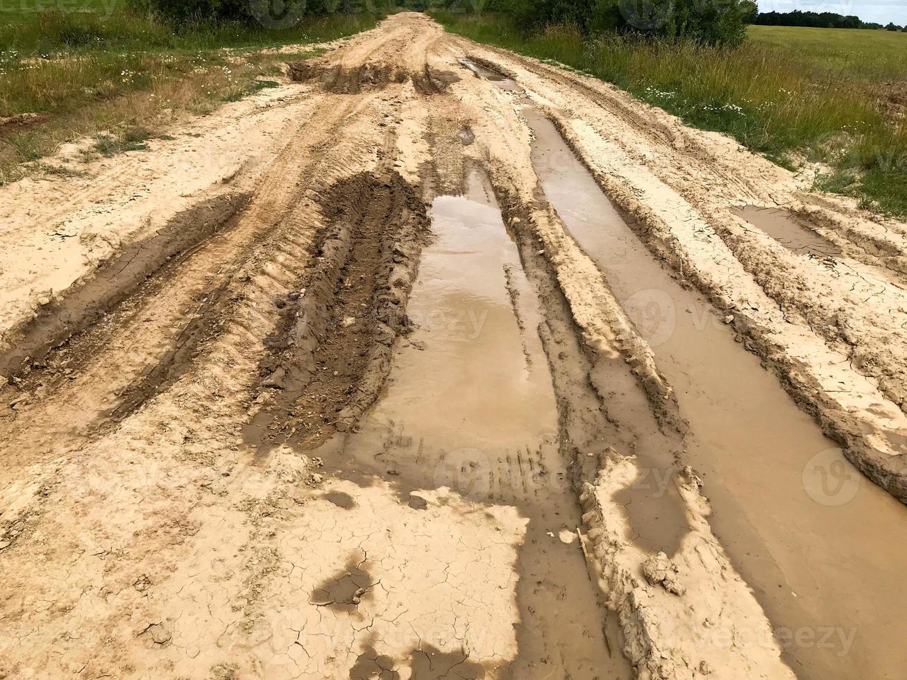 textur av en smutsig dålig smuts väg smuts väg med vattenpölar och lera torkning lera med sprickor och hjulspår. av vägen. de bakgrund foto