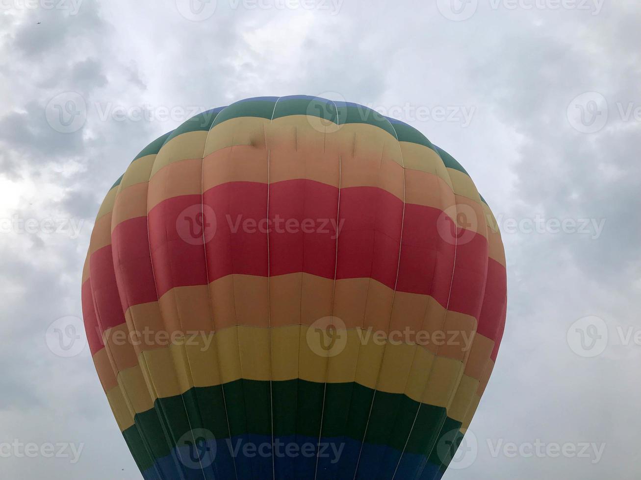 stor flerfärgad ljus runda regnbåge färgad randig randig flygande ballong med en korg mot de himmel i de kväll foto