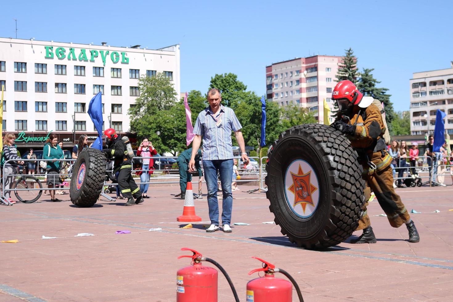 en brandman i en eldfast kostym och en hjälm kör och vänder en stor sudd hjul i en brand stridande konkurrens, belarus, minsk, 08.08.2018 foto