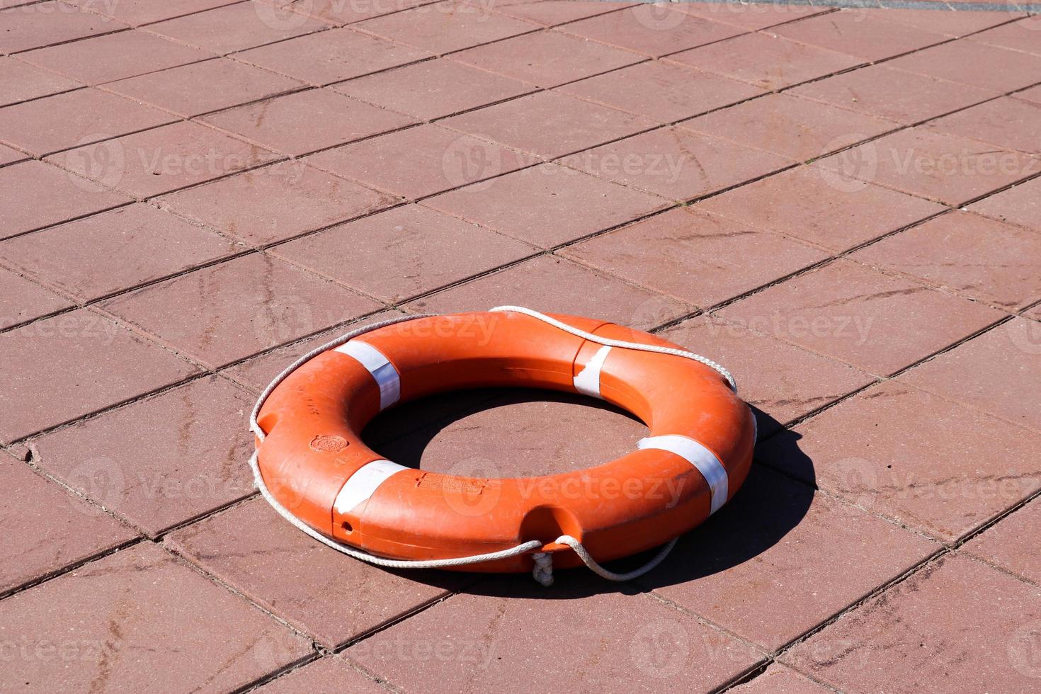 en stor runda orange plast liv ringa för säkerhet och rädda människor i de vatten lögner på de sten golv foto
