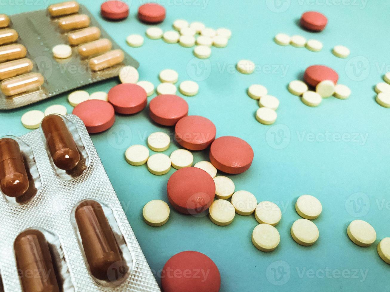 runda flerfärgad röd och gul medicinsk farmaceutisk mediciner för de behandling av sjukdomar dödande bakterier och virus piller och vitaminer blåsor från coronavirus på en blå bakgrund foto