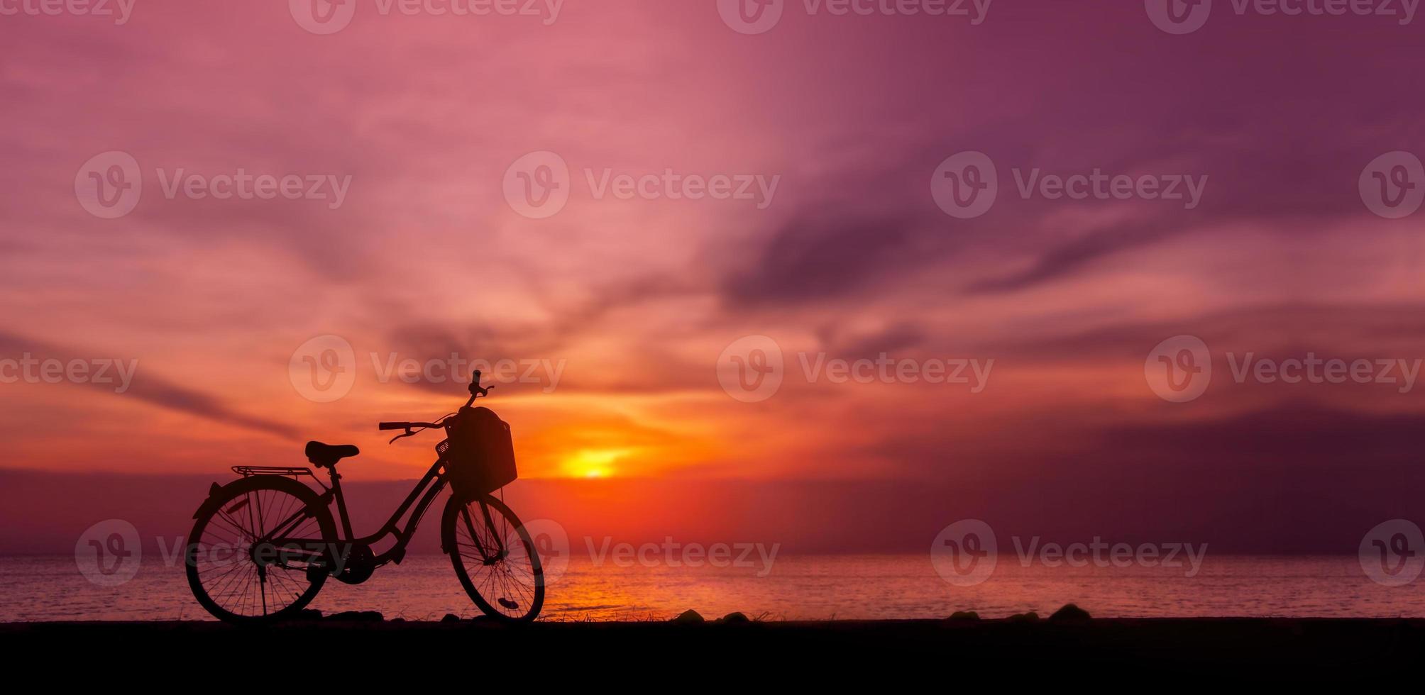 silhuett Foto av cykel parkera i främre av de sjö i solnedgång. skymning himmel och sjö som bakgrund. en noll kol fordon omgiven förbi natur. miljö vård och hållbar livsstil