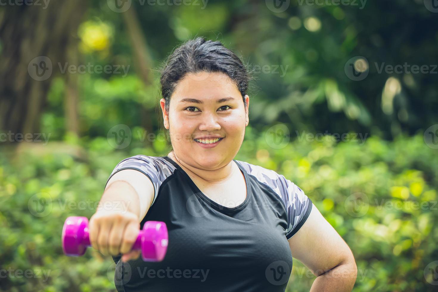 fett flicka Lycklig leende med hantel sport utomhus- övning för friska och diet foto