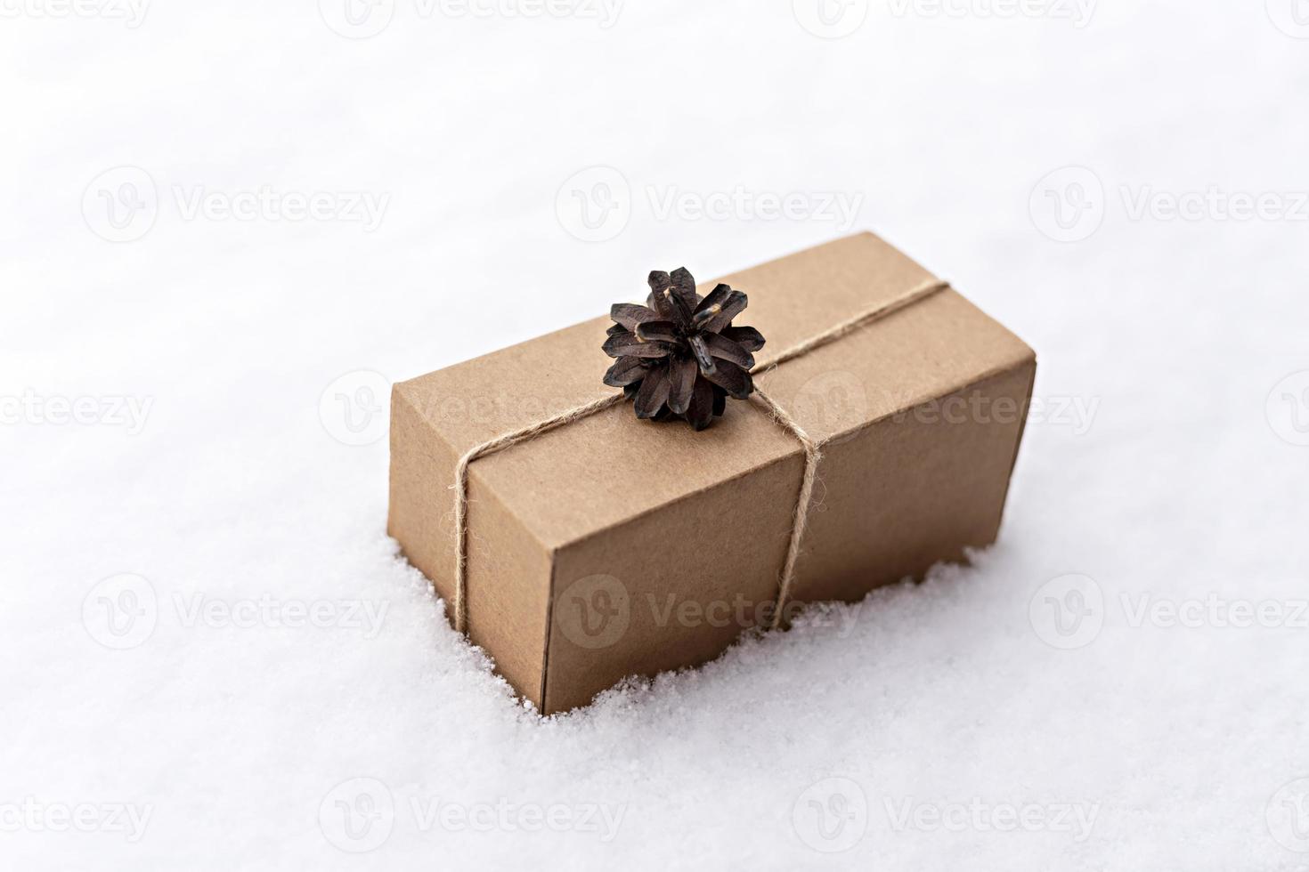gåva i en hantverk låda dekorerad med en tall kon på vit snö, eco vänlig begrepp jul och ny år högtider noll avfall foto