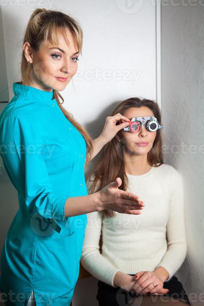 söt ung brunett kvinna checkar syn i ett ögonläkare med korrigerande linser foto
