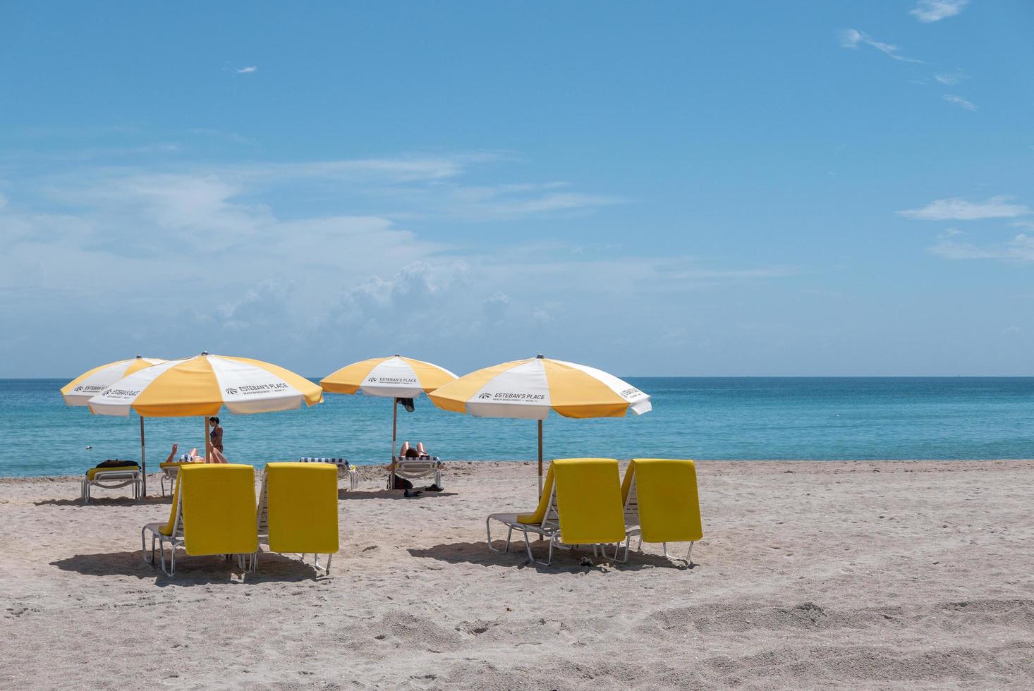 miami, florida, 2020 - strandbesökare med gult paraply och stolar på stranden foto