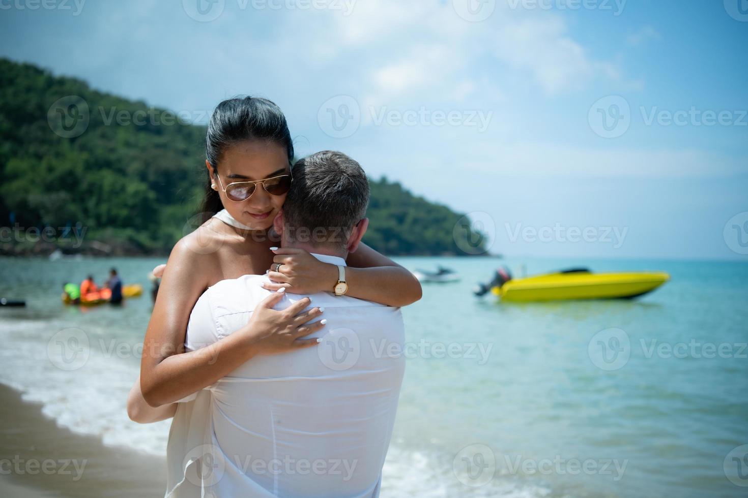 en ung vit man be för ett asiatisk flicka till gifta sig med en diamant ringa på en strand foto