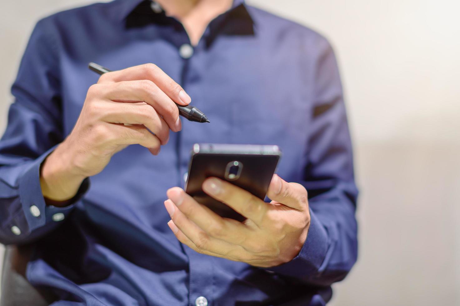 affärsman med en smartphone och en penna för att göra anteckningar foto