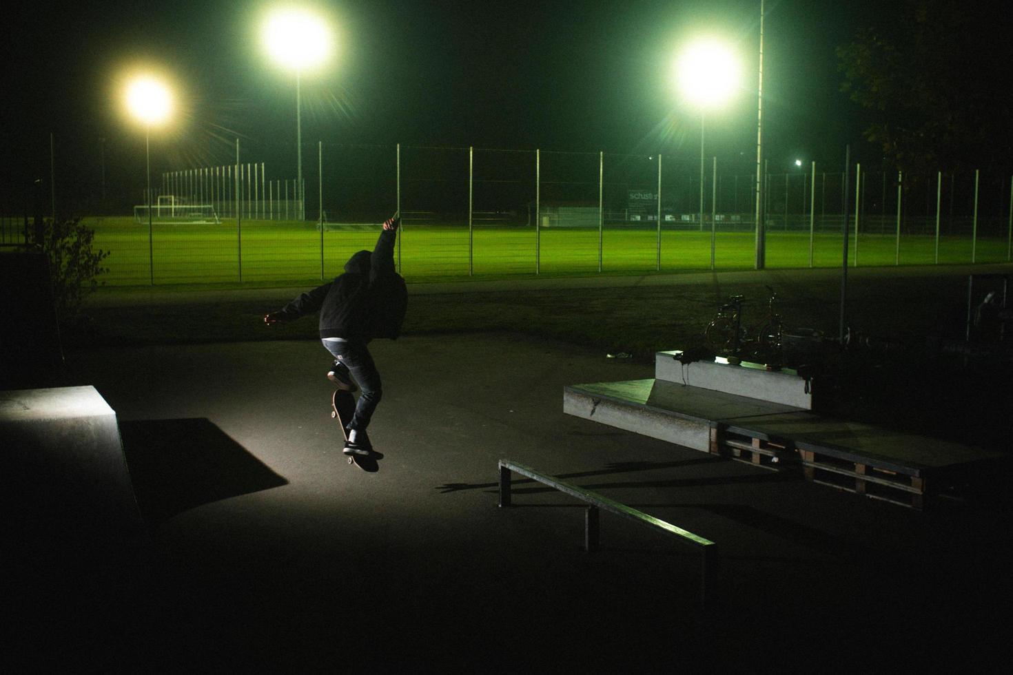 augsburg, tyskland, 2020 - ung man gör tricks på en skateboard på natten foto