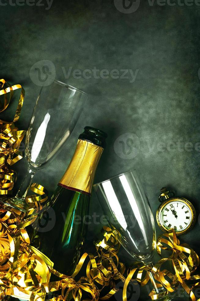 Lycklig ny år. champagne flaska med två glasögon, gyllene streamers och antik klocka med kopia Plats. ny år eve firande begrepp bakgrund foto