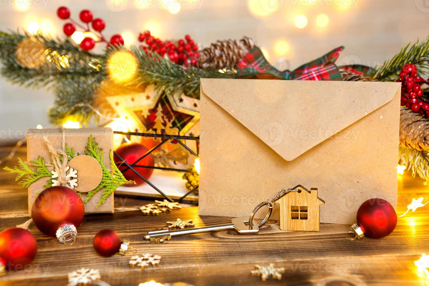 nyckel till huset med en nyckelring på ett bord med juldekor. en present till nyår, jul. bygga, designa, projektera, flytta till nytt hus, belåna, hyra och köpa fastigheter. kopieringsutrymme foto