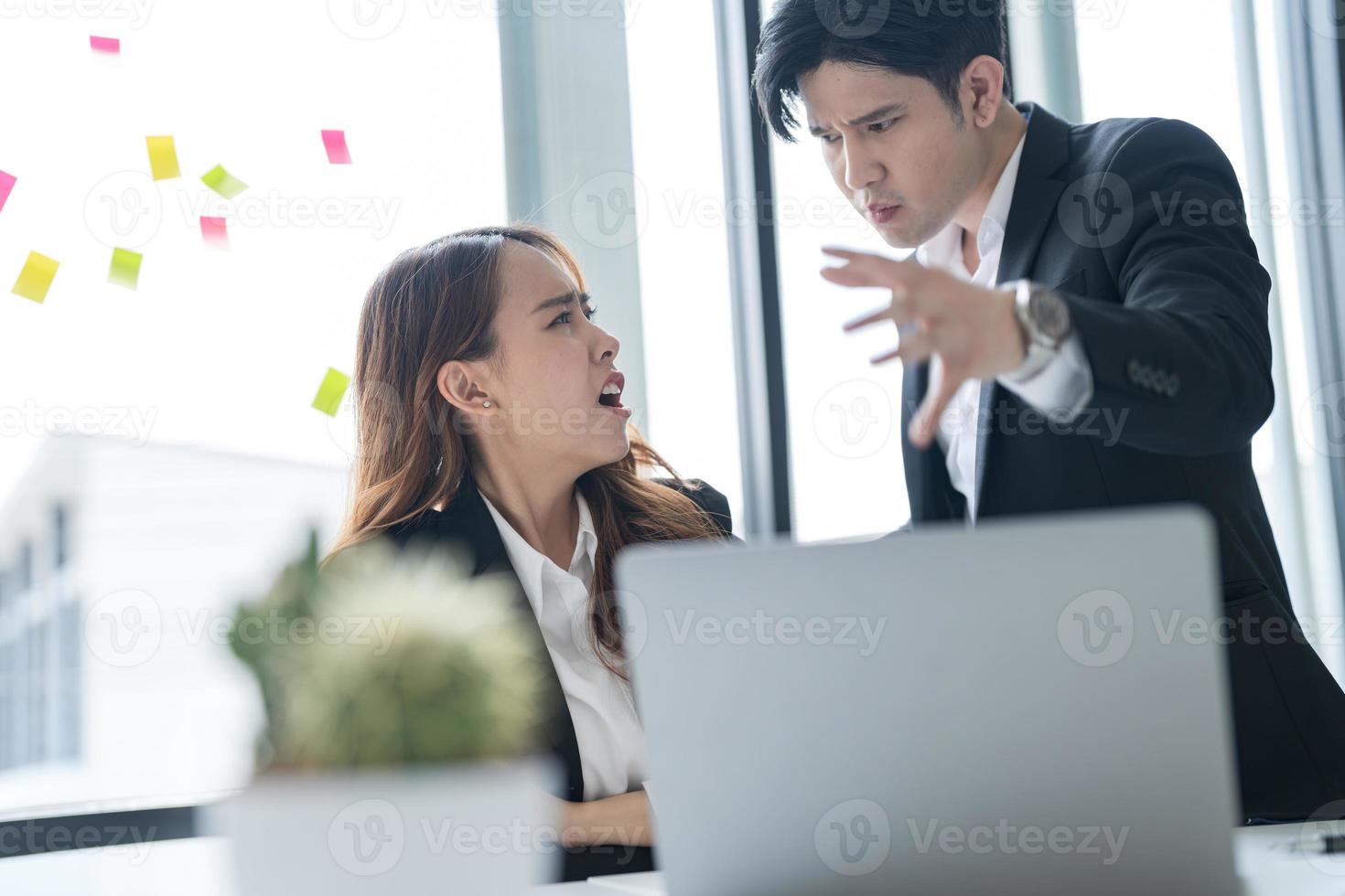 företag människor Sammanträde tillsammans på en skrivbord använder sig av bärbara datorer i de kontor de två av dem hade en allvarlig, orolig uttryck på deras ansikten medan arbetssätt tillsammans foto