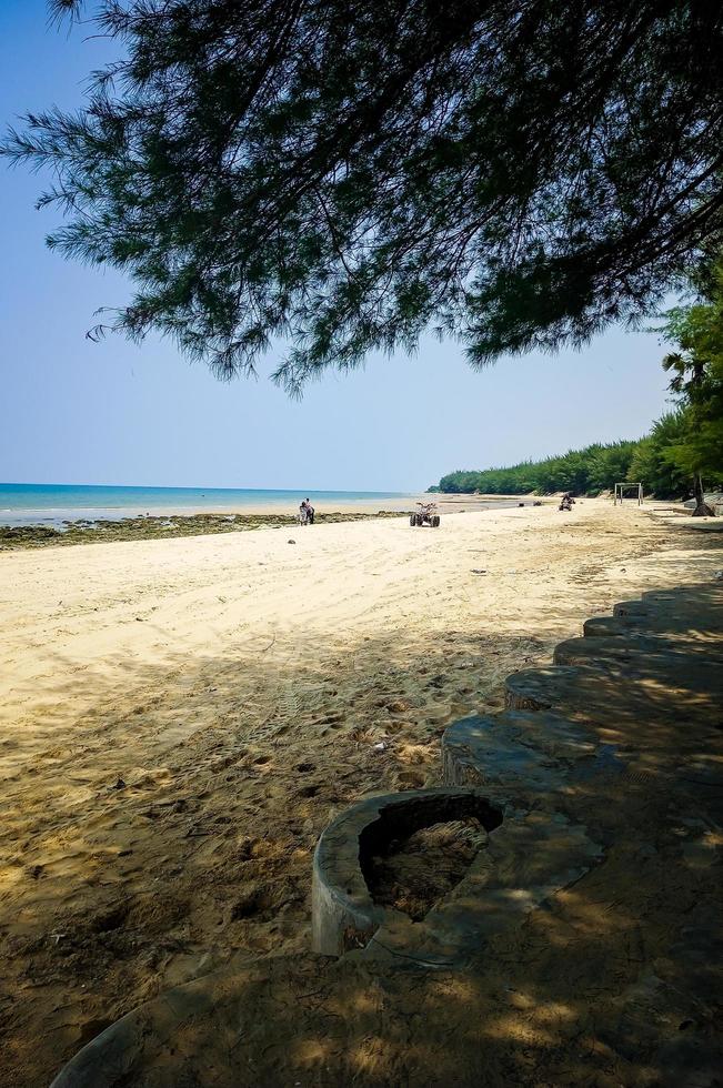 se på de strand med vit sand, hav vågor, och blå himmel. också sett är en räka tall träd som har de latin namn casuarina equisetifolia foto