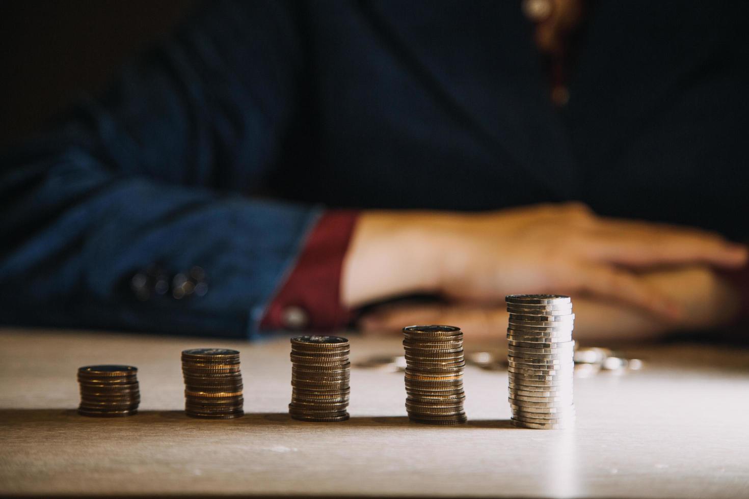 sparande pengar hand sätta mynt på stack på tabell med solsken. begrepp finansiera och bokföring foto