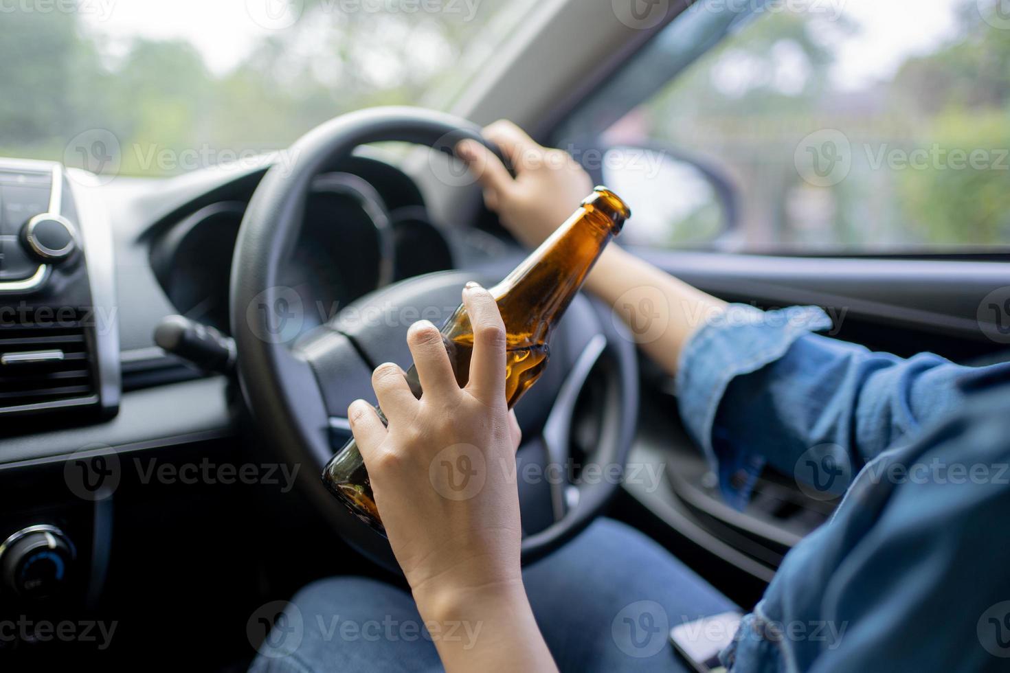 hand innehav alkoholhaltig flaska medan körning, närbild. foto