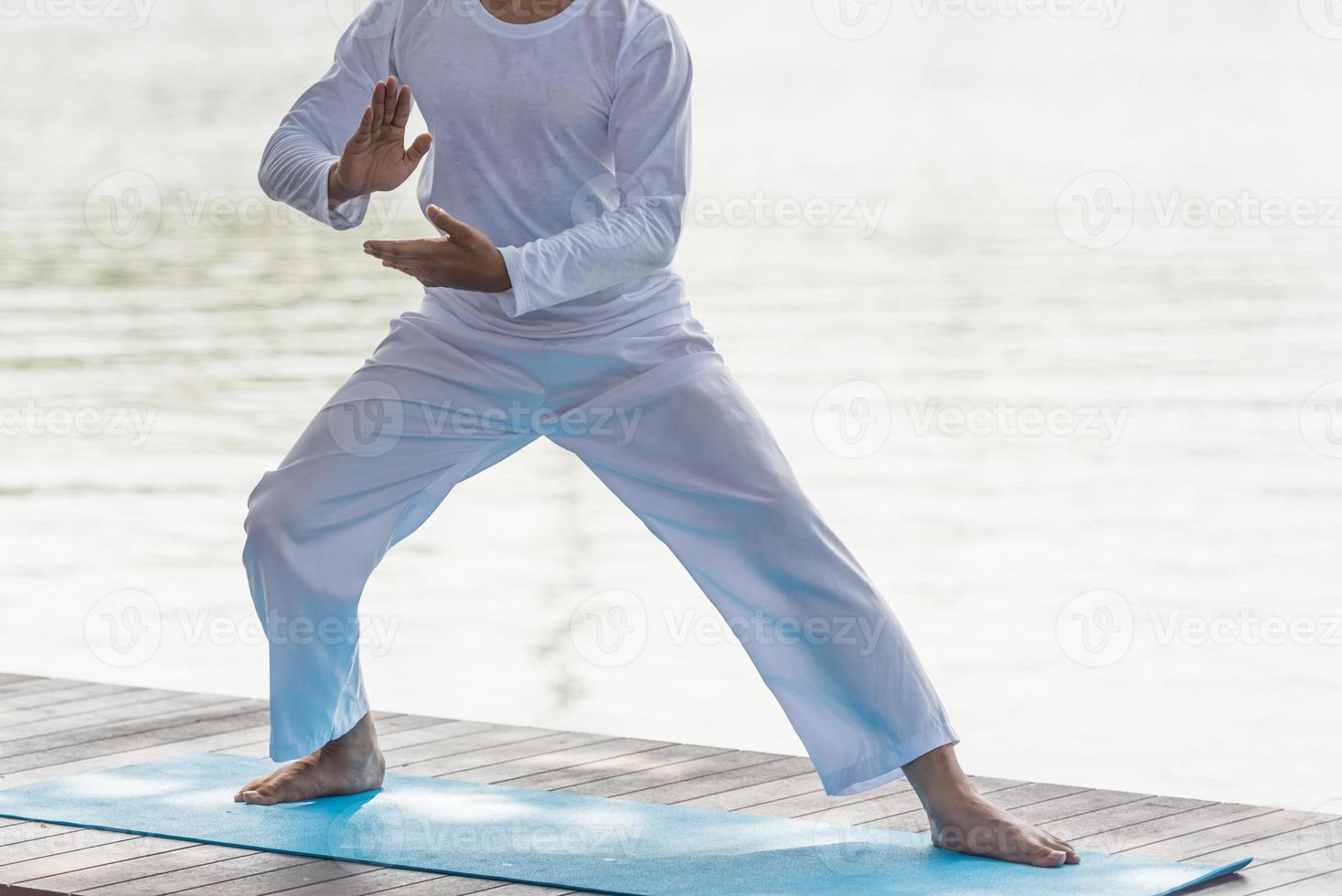 ung man praktiserande traditionell tai chi chuan, tai ji och qi gong i de parkera för friska, traditionell kinesisk krigisk konst begrepp på naturlig bakgrund . foto