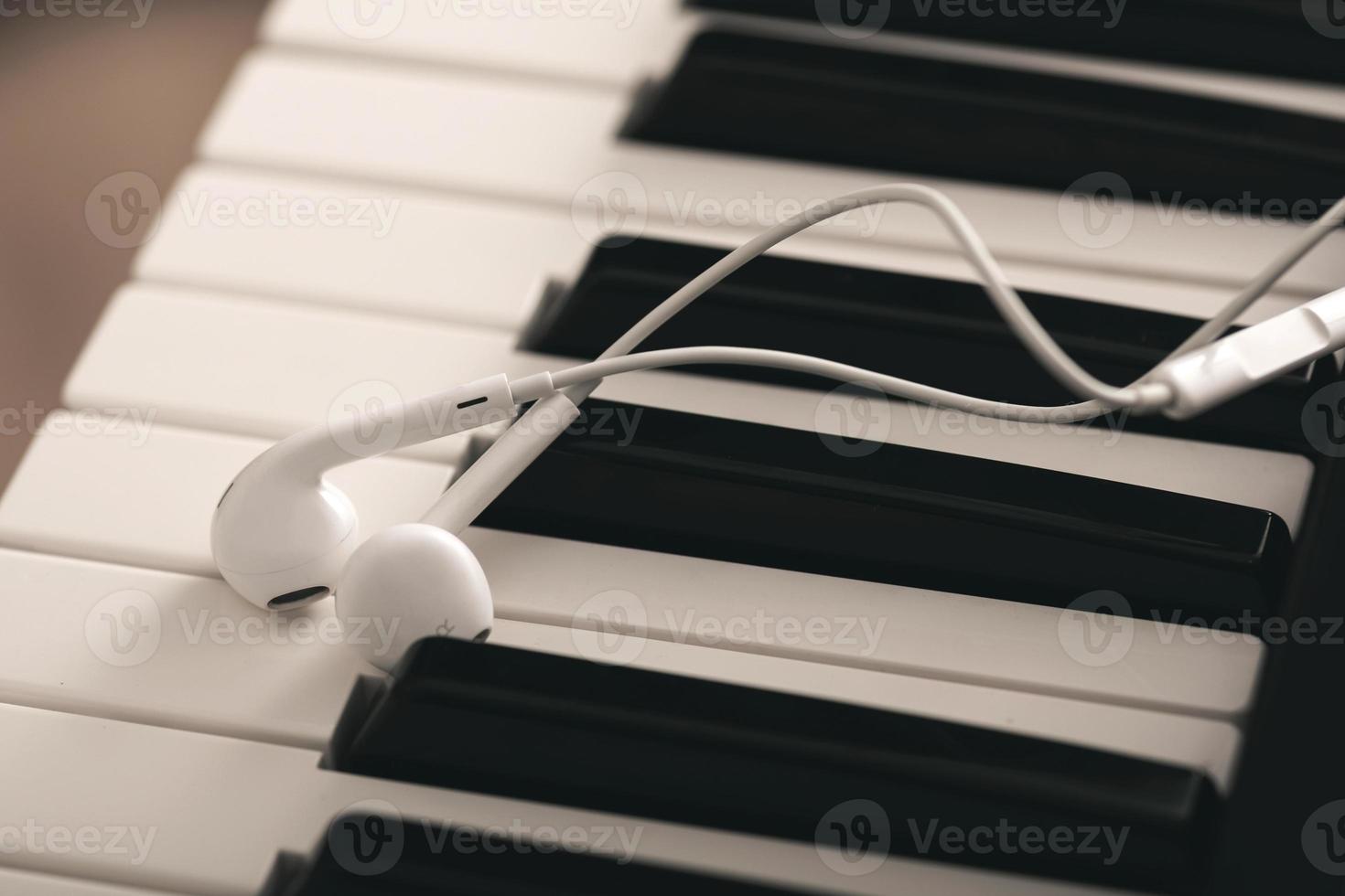 närbild av hörlurar över piano eller synthesizer tangentbord foto