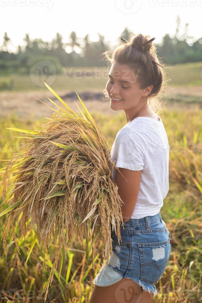 Lycklig kvinna jordbrukare under skörd på de ris fält foto