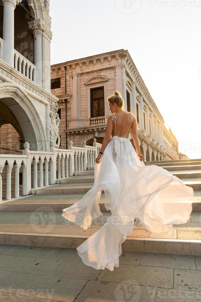 kvinna bär skön vit klänning gående på en gata av de Venedig stad foto