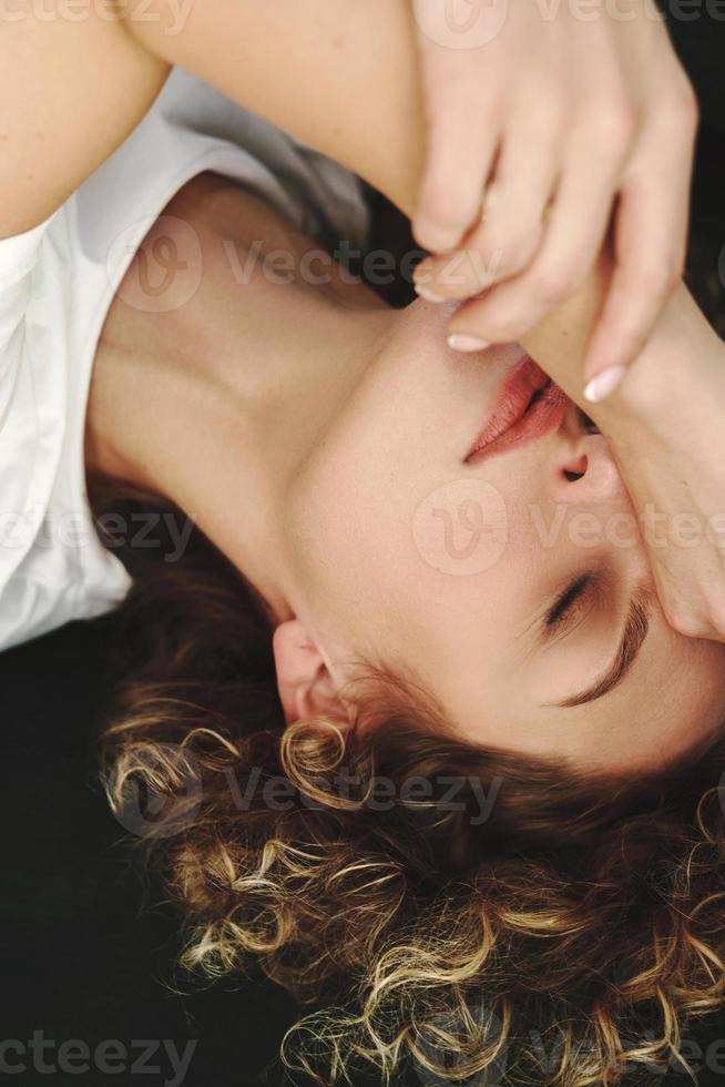 skön kvinna med lockigt hår liggande på grön soffa foto