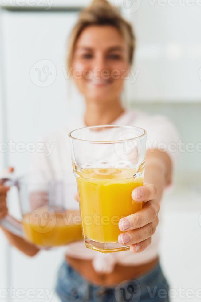 ung glad kvinna med stor glas av färsk orange juice foto