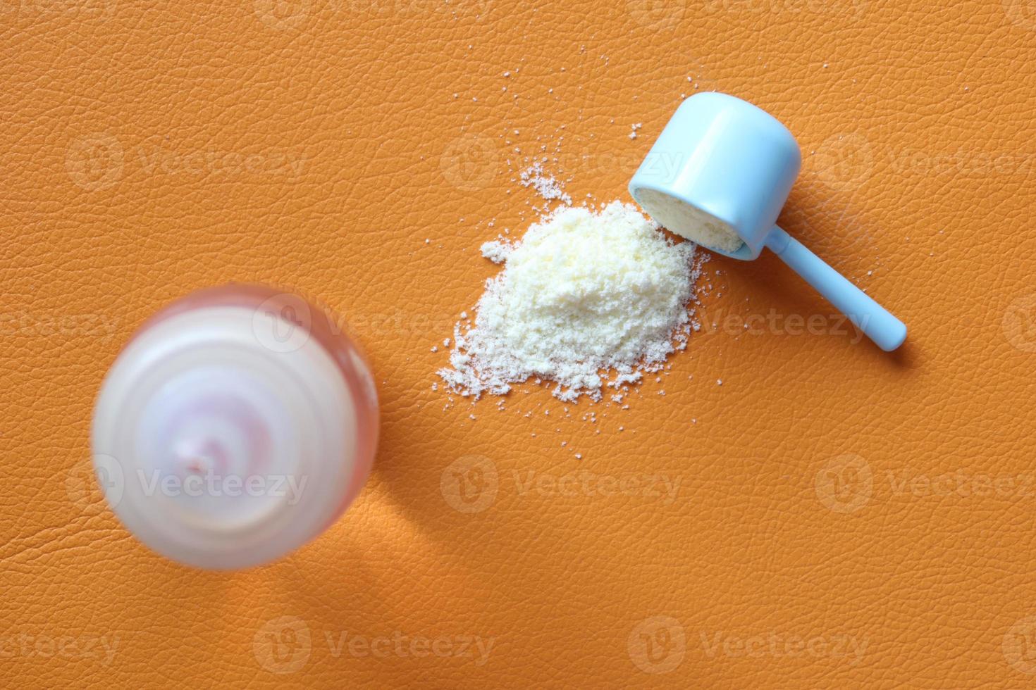 stänga upp av bebis mjölk pulver och sked orange bakgrund foto