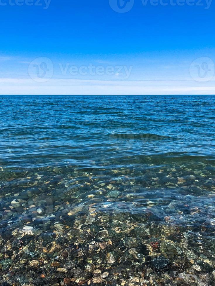 skön flerfärgad runda stenar på de hav, floder, sjöar, damm, hav och kokande vatten med vågor på de klippig strand av en tropisk värma tillflykt på de horisont och himmel. vertikal se foto