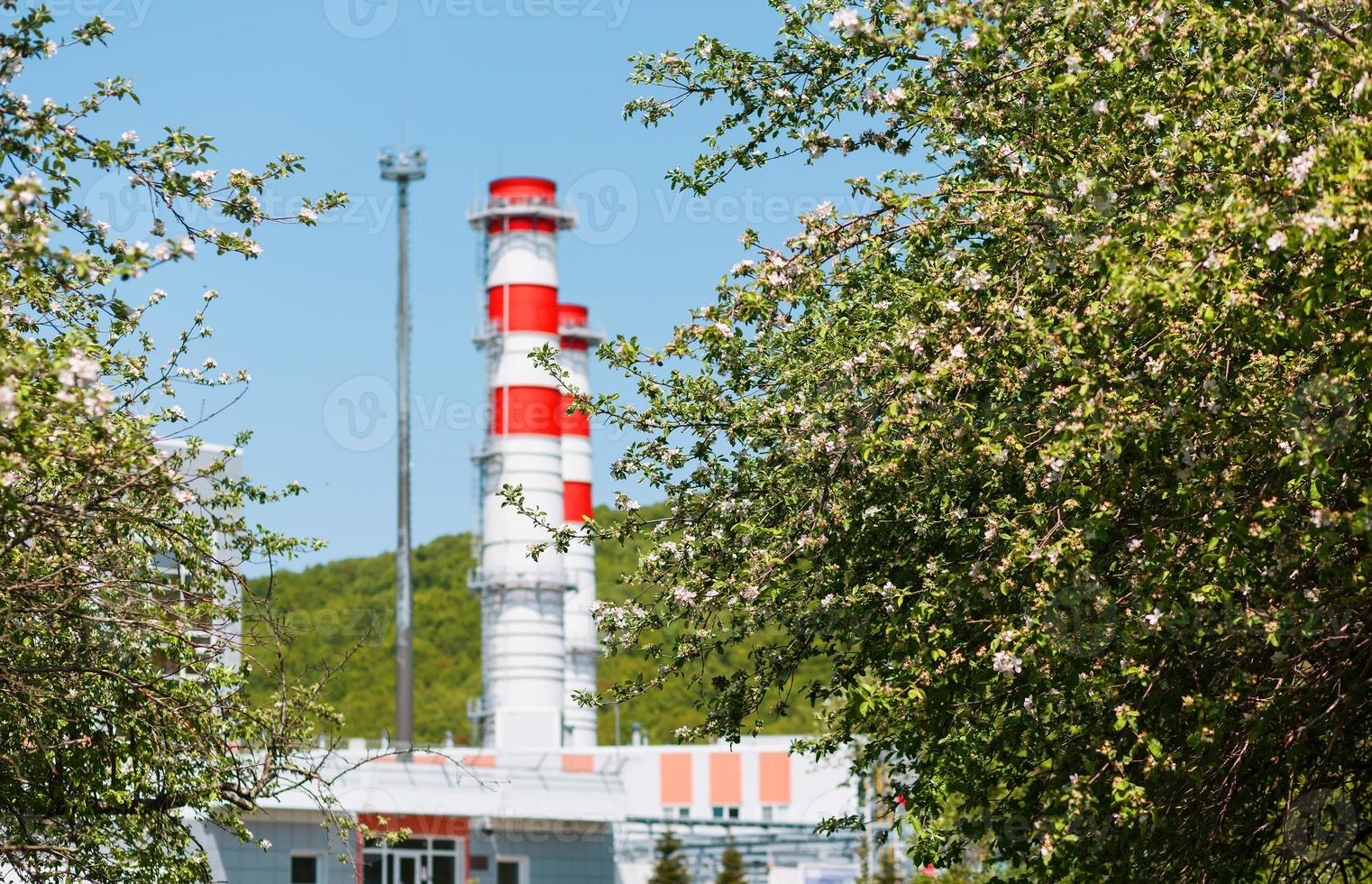 gas turbin kraft växt på naturlig gas med skorstenar av röd vit Färg mot de blå himmel i de äpple fruktträdgård foto