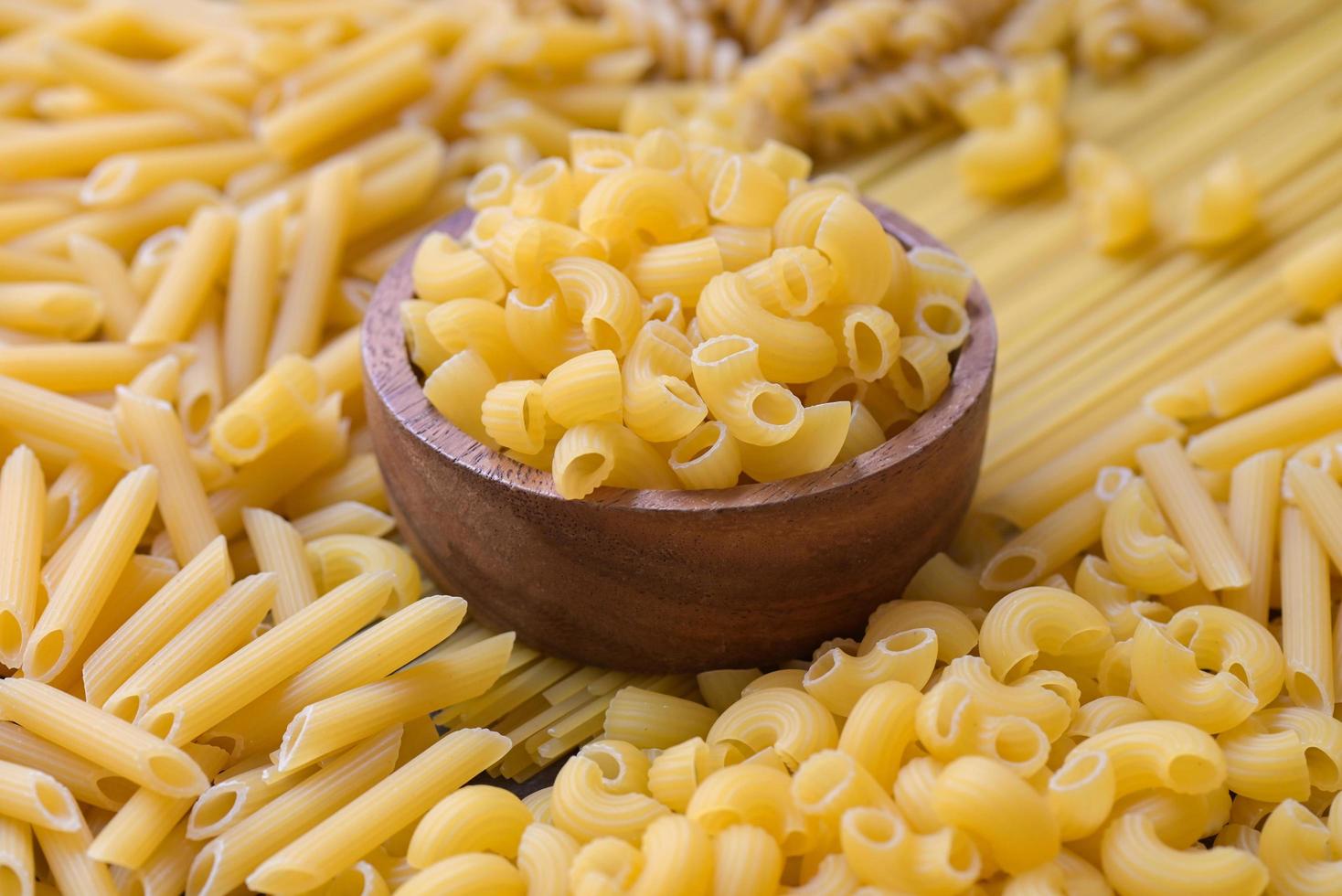 rå pasta olika typer av okokt pasta makaroner spaghetti och spaghetti på bakgrund - topp se, italiensk mat kulinariska begrepp, samling av annorlunda rå pasta på matlagning tabell för matlagning mat foto