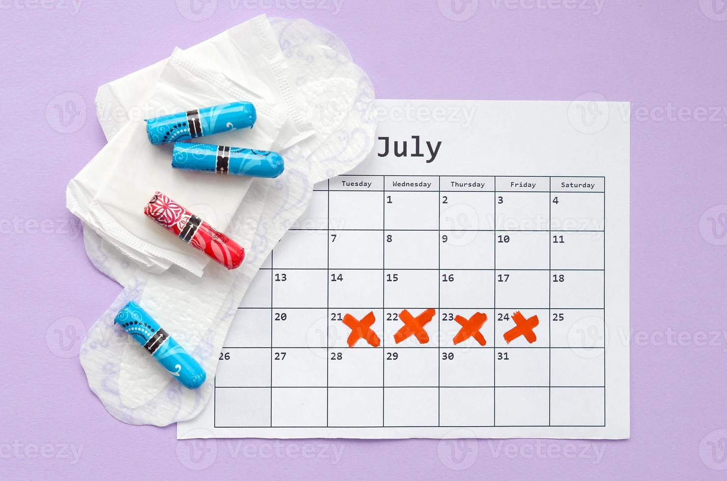 menstruations- dynor och tamponger på menstruation period kalender platt lägga på lila bakgrund foto