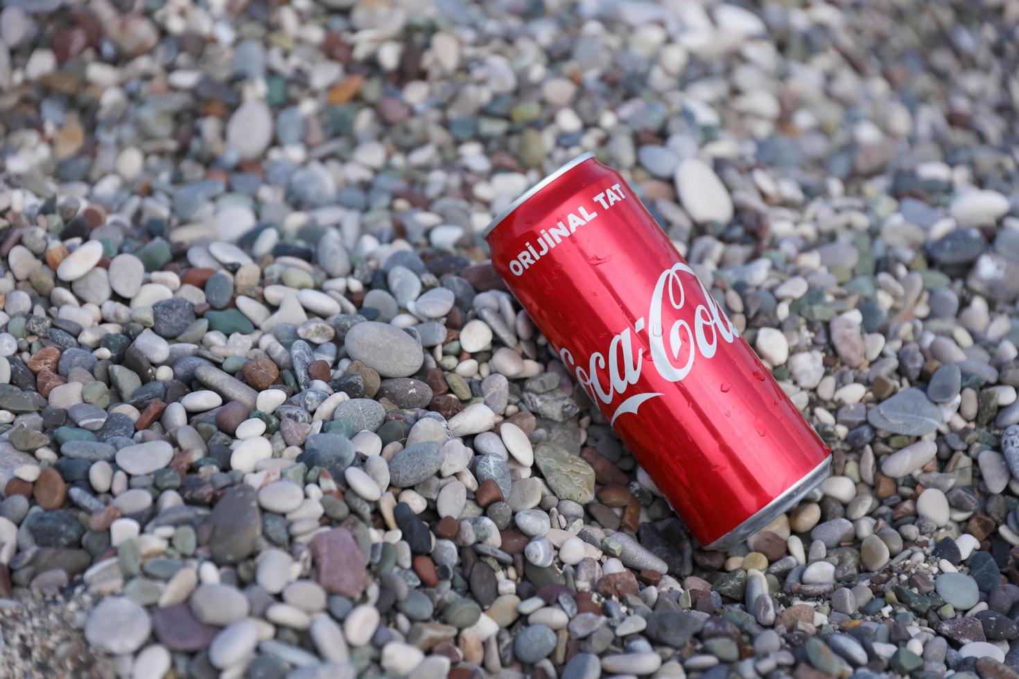 antalya, Kalkon - Maj 18, 2022 original- coca cola röd tenn kan lögner på små runda sten stenar stänga till hav Strand. Coca Cola på turkiska strand foto