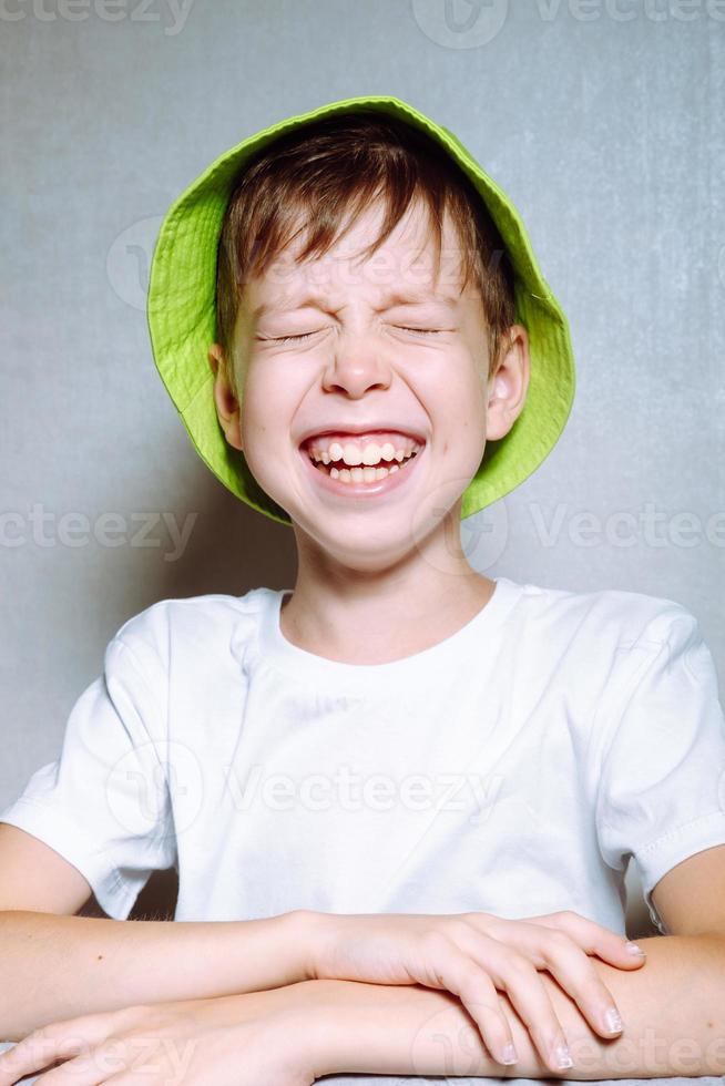 porträtt av en nyckfull pojke i en ljus grön panama hatt, på en vit bakgrund foto