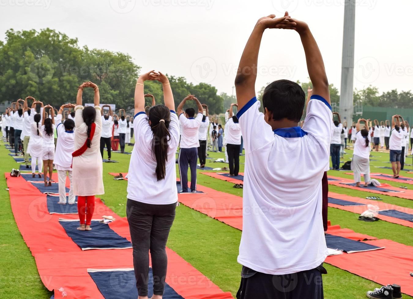 grupp yoga övning session för människor av annorlunda ålder grupper på cricket stadion i delhi på internationell yoga dag, stor grupp av vuxna delta yoga session foto