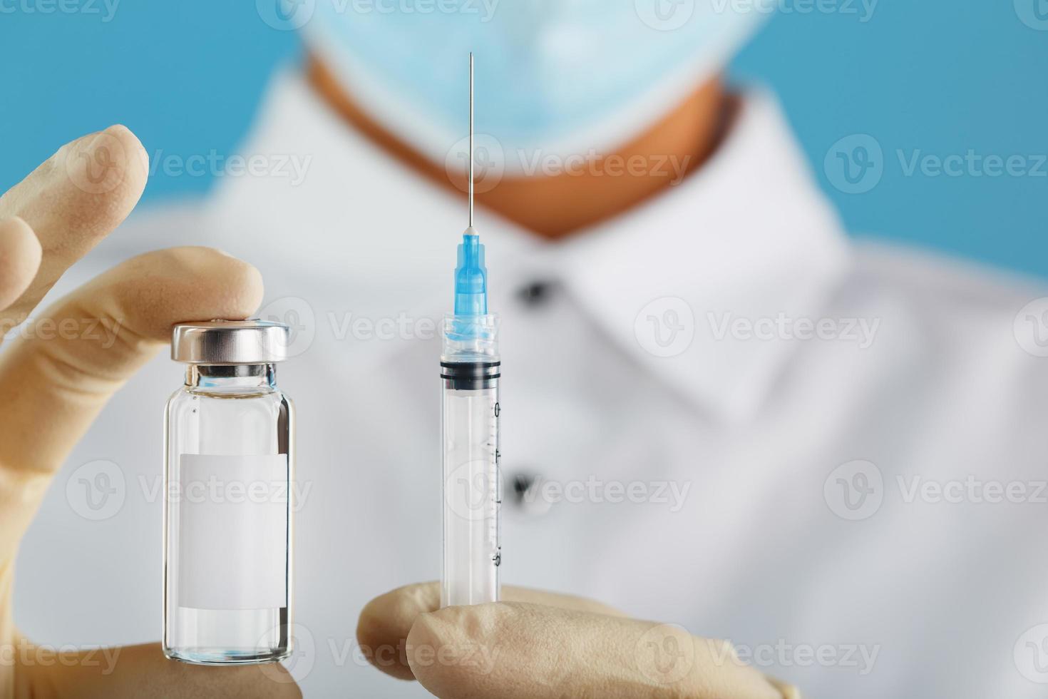 en läkare i sudd handskar innehar ett ampull med en vaccin och en spruta, närbild. foto