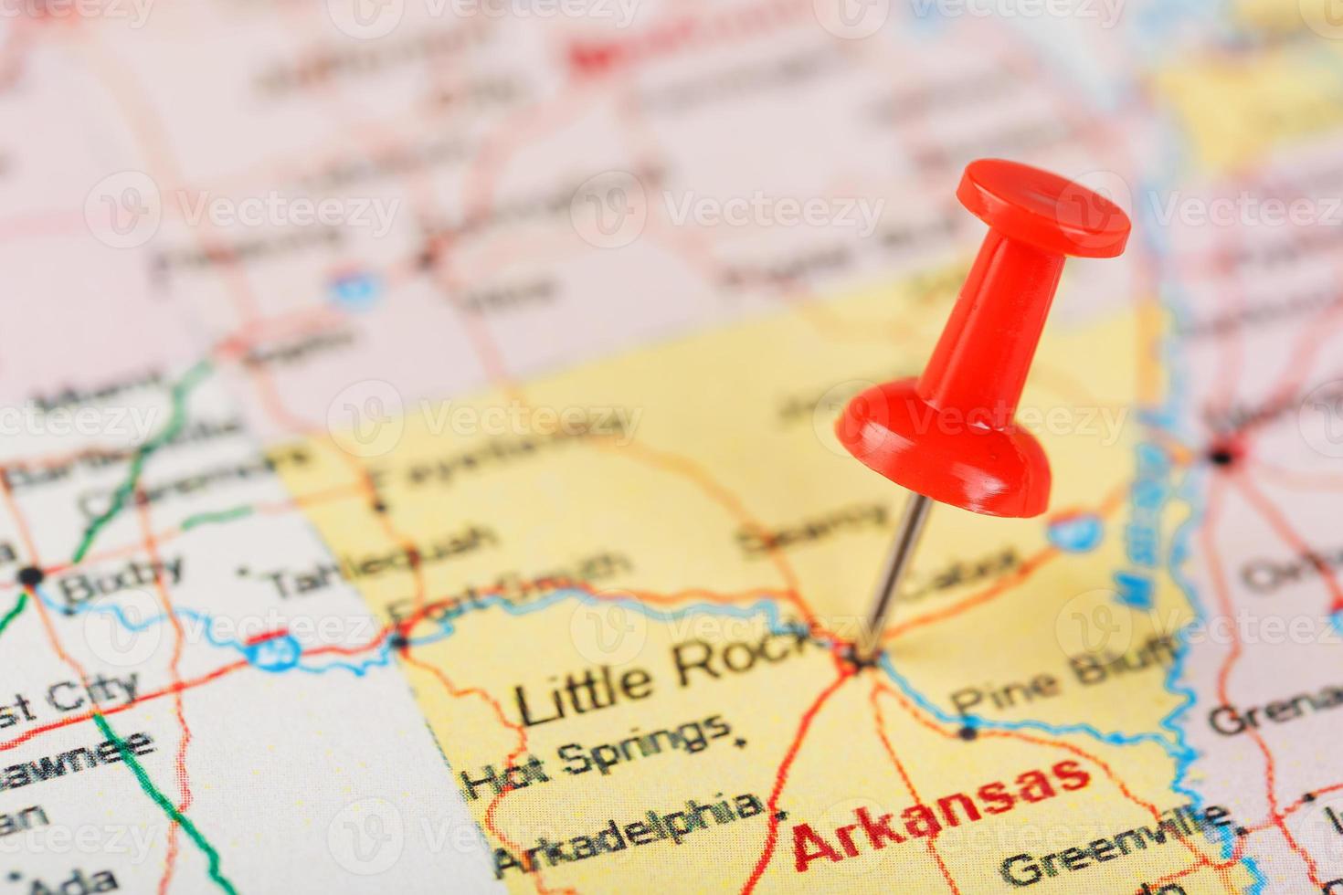 röd prästerlig nål på en Karta av usa, Arkansas och de huvudstad liten sten. stänga upp Karta av Arkansas med röd kryssa foto