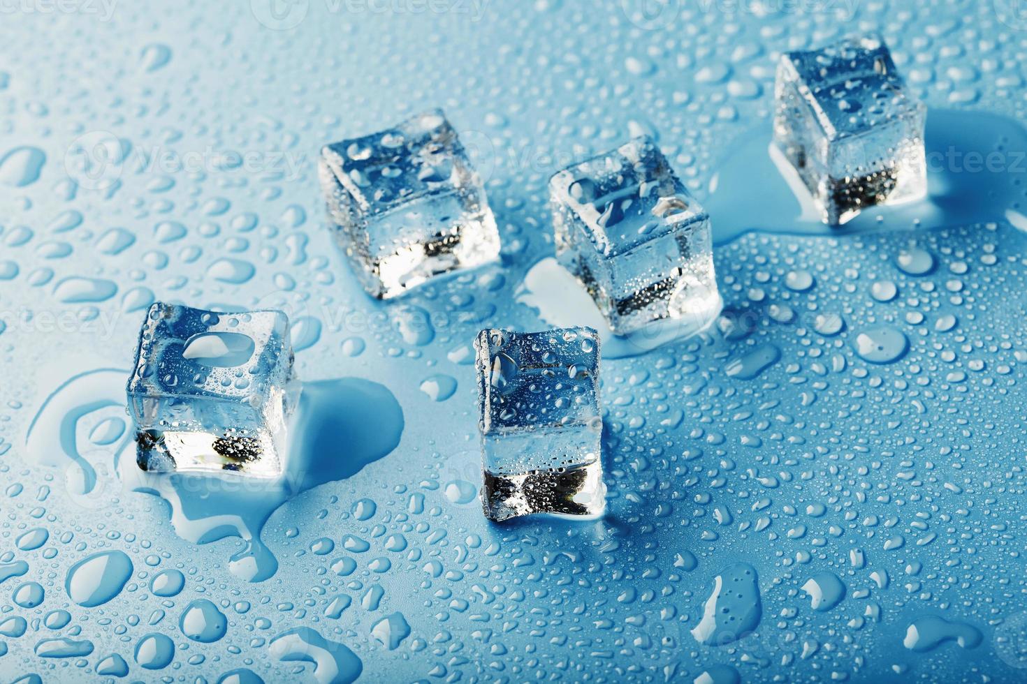 is kuber med droppar av smälta vatten vatten på en blå bakgrund, topp se. foto
