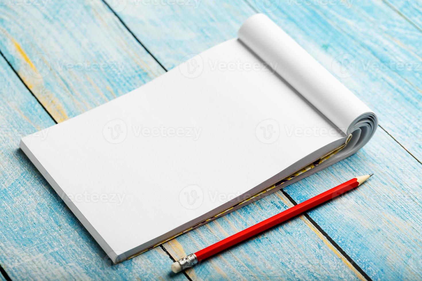 anteckningsblock med röd penna på en blå trä- tabell bakgrund, för utbildning, skriva mål och gärningar foto