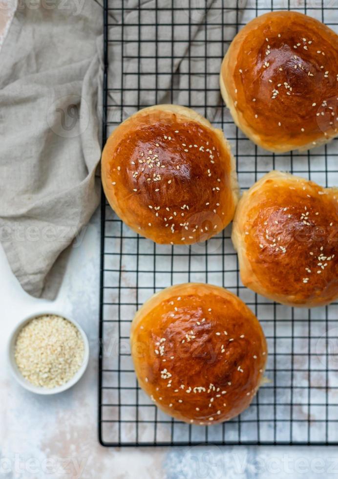 runda bullar med sesam frön, bröd rullar. gott hemlagad burger bröd med sesam, betong bakgrund. nyligen bakad hamburgare bullar. topp se. foto