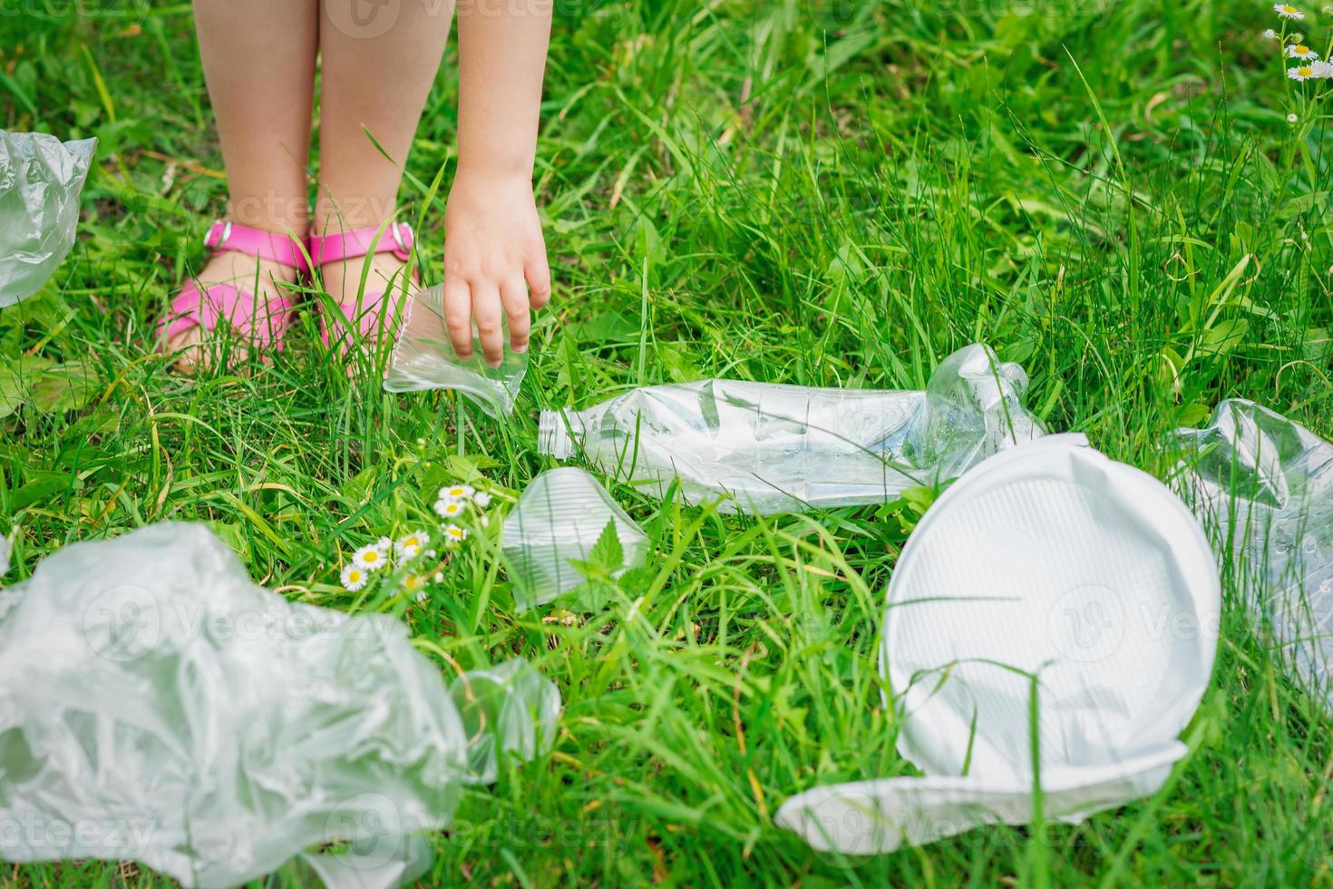 hand av barn rengör grön gräs från plast skräp foto