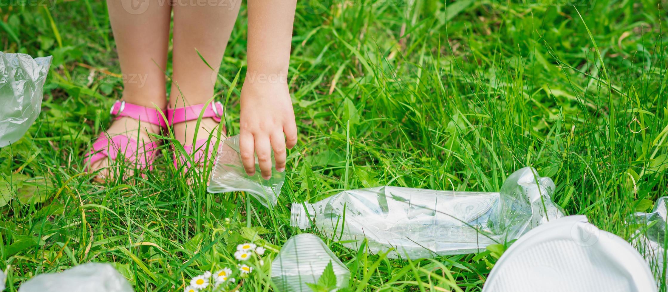 hand av barn rengör grön gräs från plast skräp foto