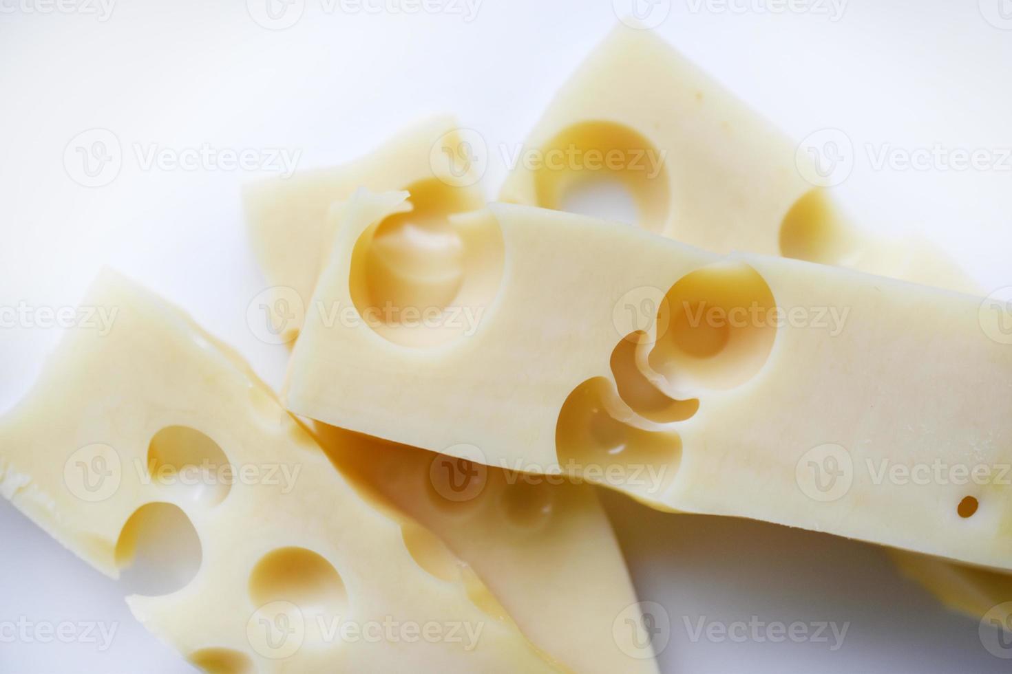 bitar av gul ost med stor hål på en vit bakgrund. utsökt ost närbild. foto