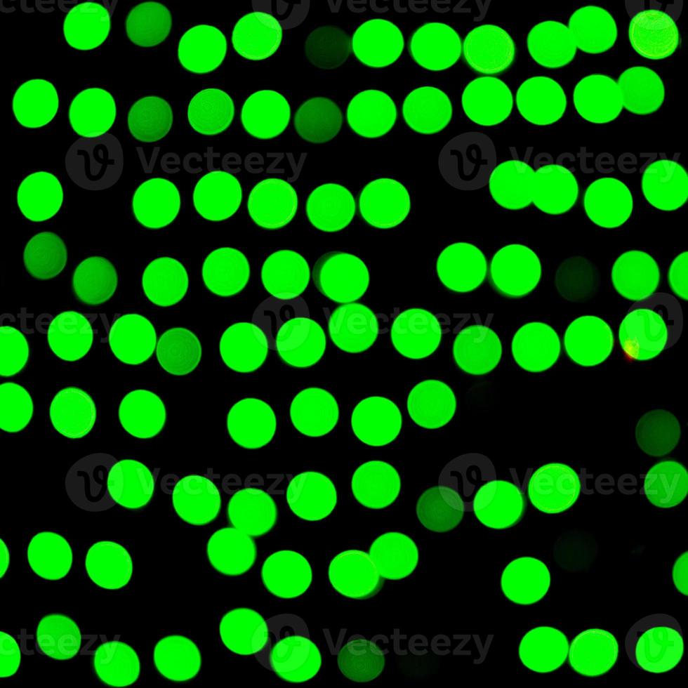 ofokuserad abstrakt grön bokeh på svart bakgrund. defocused och suddig många runda ljus foto