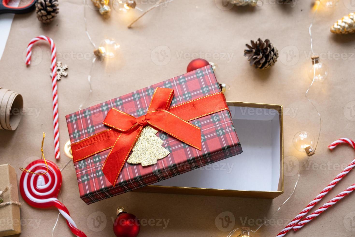 packa en gåva för jul och ny år i kraft papper, kottar, tejp, sax. taggar med falsk upp, naturlig dekor, hand gjord, själv. festlig humör. flatlay, bakgrund foto