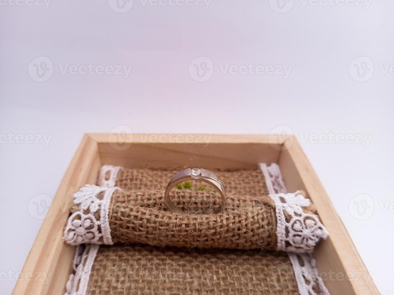bröllop ringa placerad på en trä- ringbox med en säckväv trasa som en bas. med vit isolerat bakgrund foto