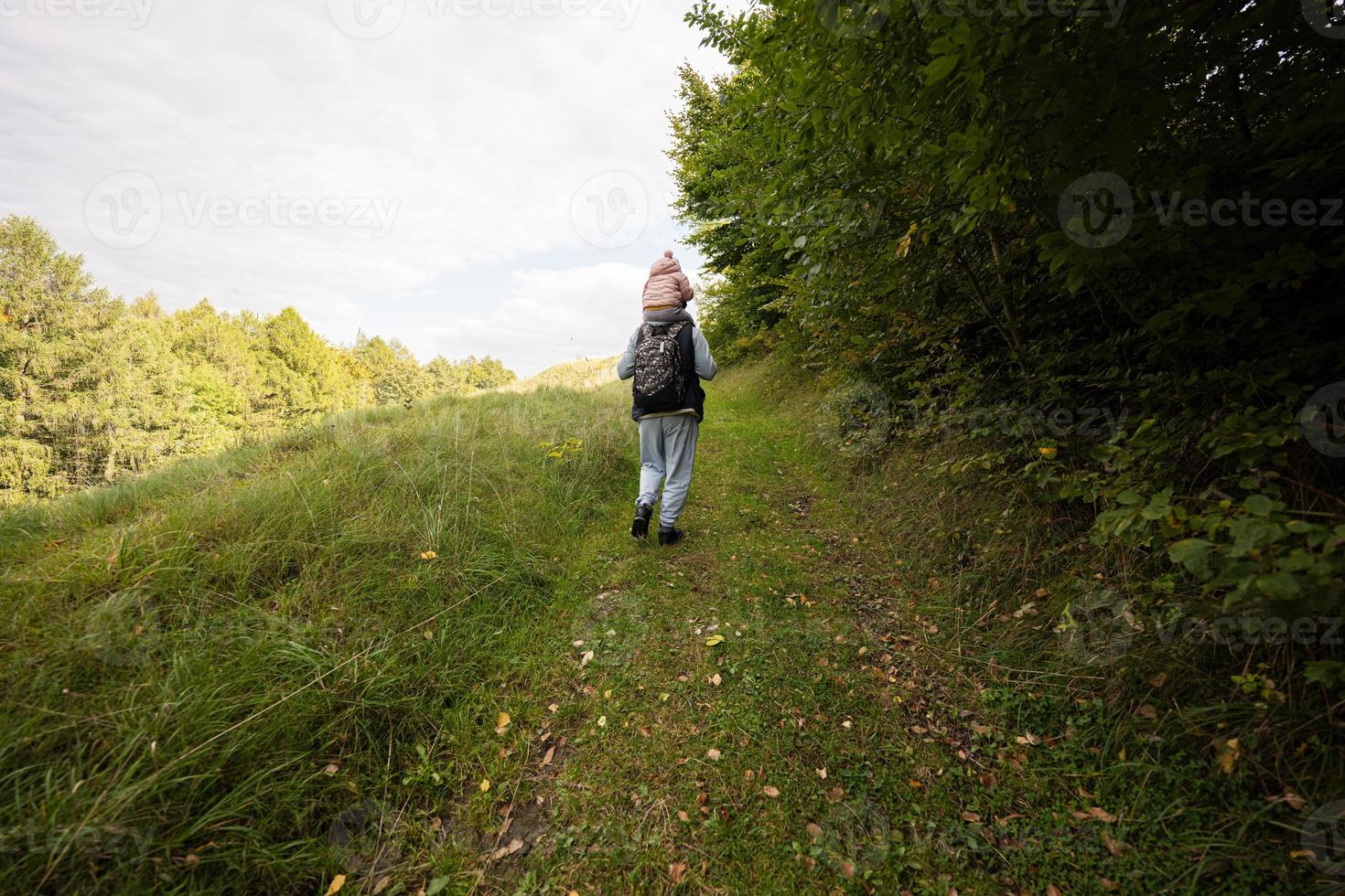 pappa med dotter på hans axlar gående i skog. foto