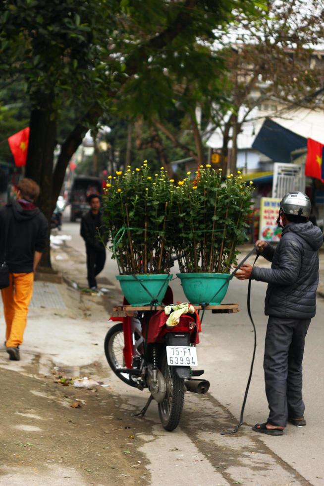 nyans, vietnam, februari 04, 2018. motorcykel med två blommor pott med gul krysantemum och motorcykel förare på en gata av stad. foto
