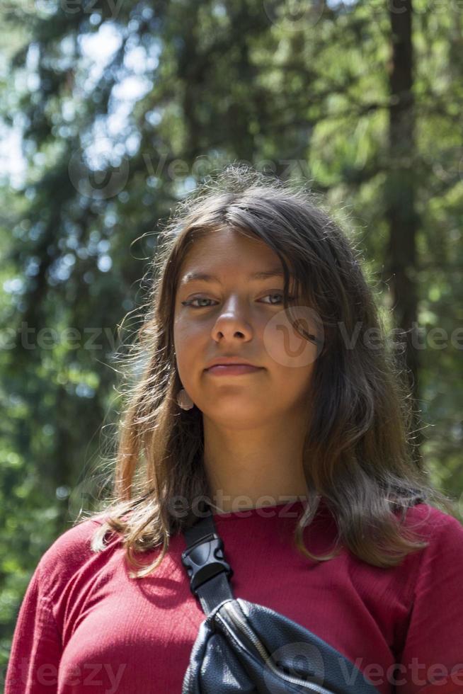 porträtt av en söt europeisk Tonårs flicka i de skog i sommar på en solig dag, en flicka i en vinröd klänning foto