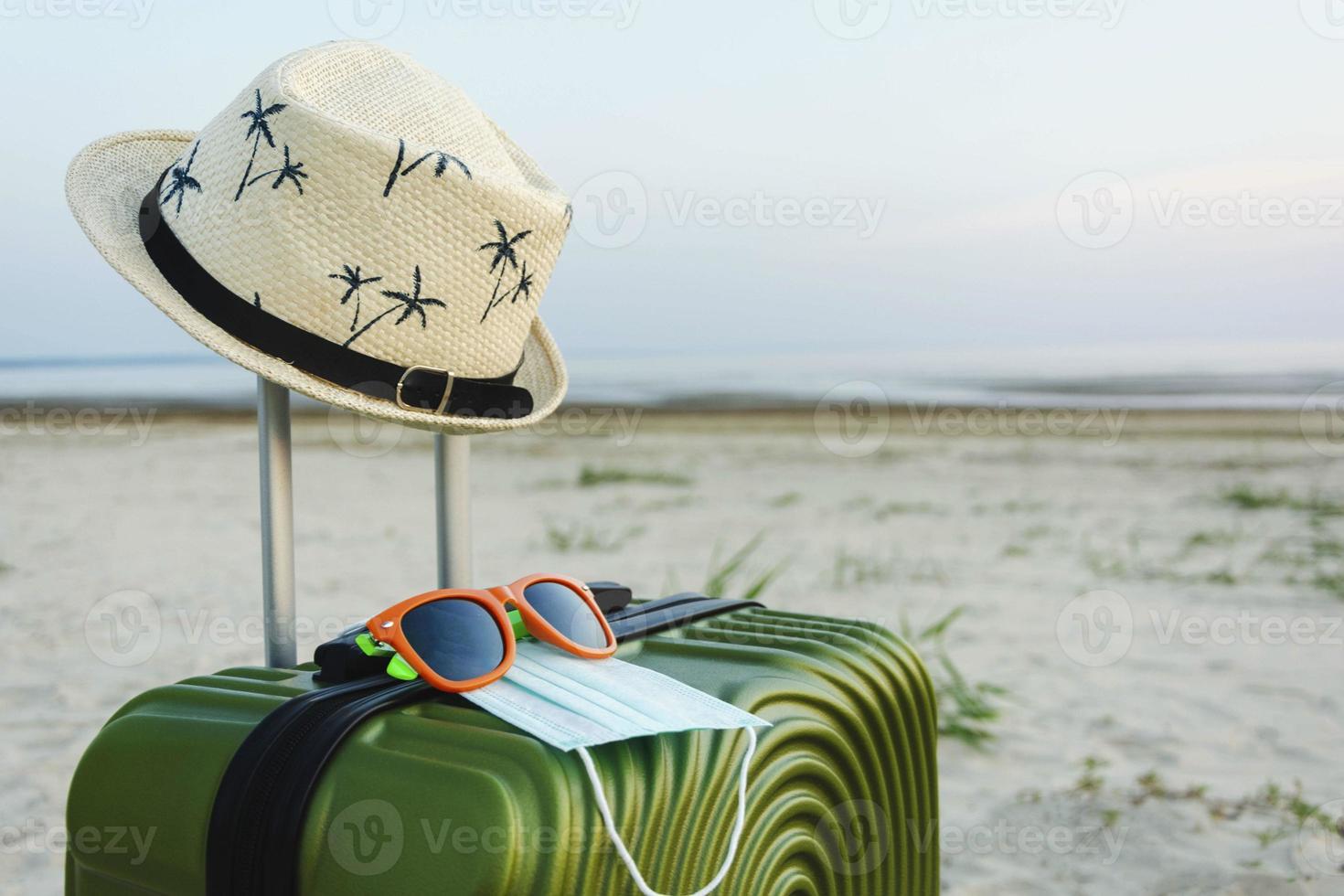 resten och resa. en resväska eller bagage väska med en Sol hatt på de strand bakgrund, plan biljetter , solglasögon, pass, semester, kopia Plats. foto