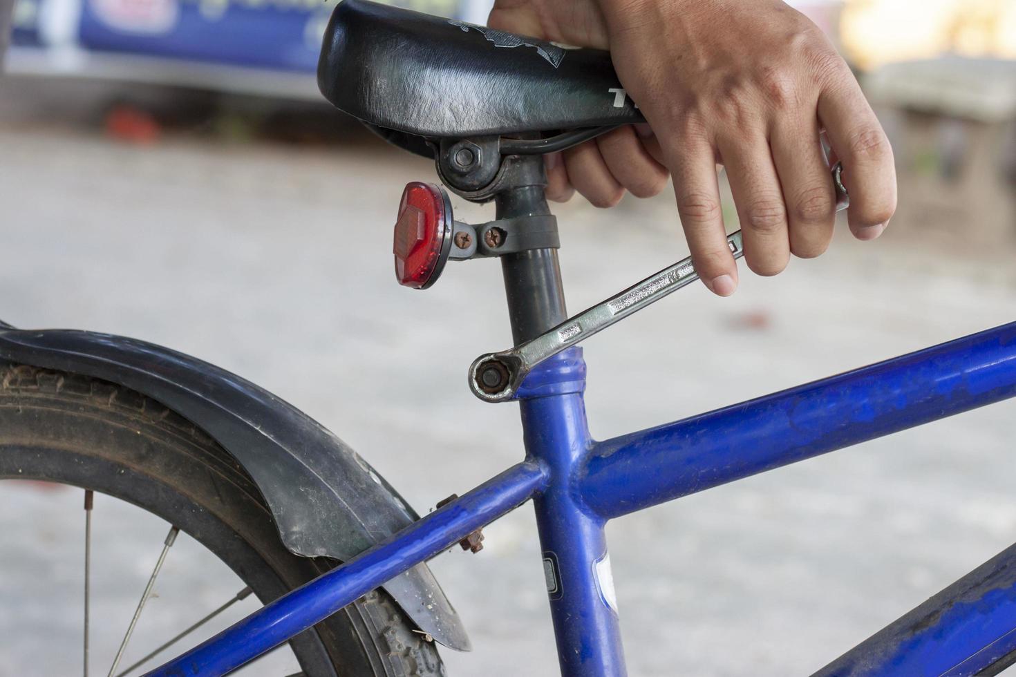 hand av de mekaniker innehar de ringa Nycklar till lossa de rostig nöt i de cykel reparera. foto