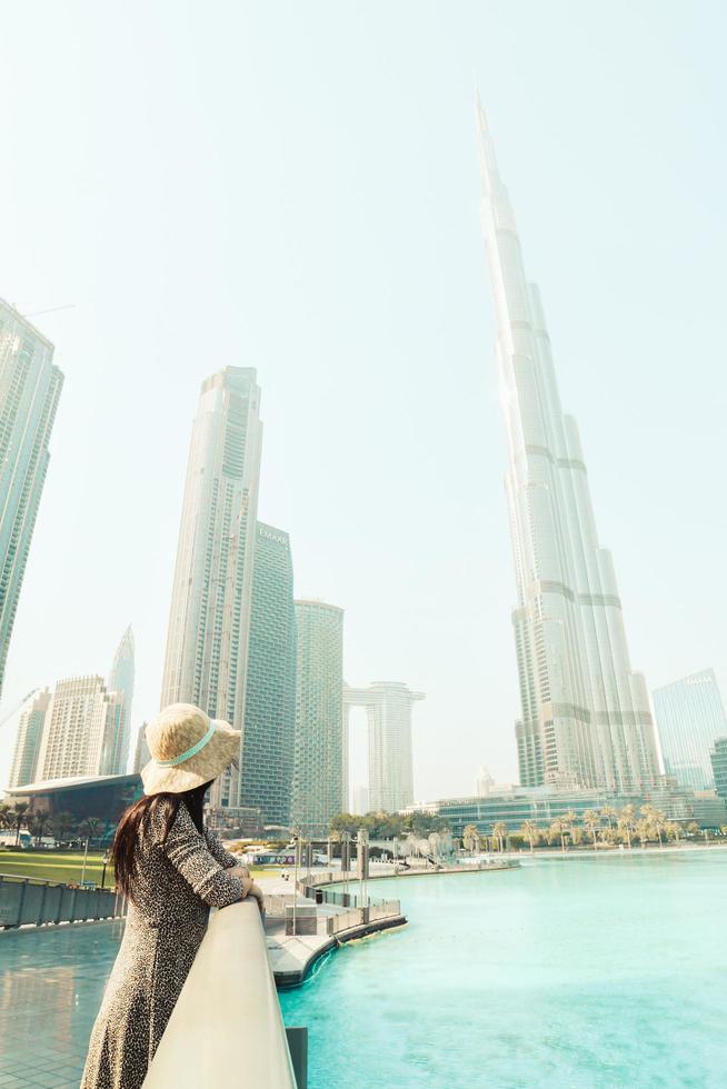 dubai, uae, 2022 -modern turist kvinna resande ser på burj khalifa torn mot dimmig vit himmel, dubai, uae foto